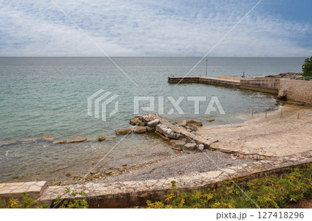 Stone pier and rocky beach on calm sea coast, Croatia. Stone pier and rocky beach on calm sea coast, Croatia. 127418296
