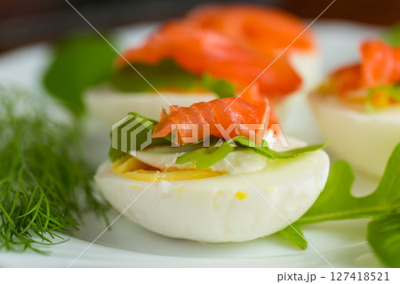 Boiled eggs with pieces of fish and herbs on top 127418521