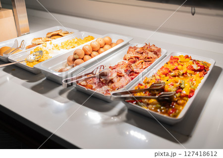 Variety of hot breakfast dishes on buffet table in hotel dining area. Morning meal options, protein-rich food, and colorful nutrition concept. Variety of hot breakfast dishes on buffet table in hotel dining area. Morning meal options, protein-rich food, and colorful nutrition concept. 127418612