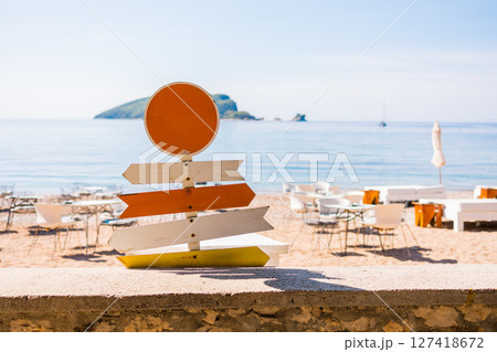 Wooden beach signpost with arrows on seaside promenade. Summer vacation, coastal leisure, and travel direction concept. 127418672