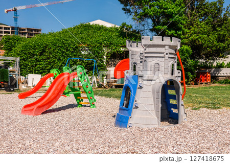 Colorful plastic playground with slides and castle structure on gravel. Outdoor recreation, children's fun zone, and imaginative play environment concept. Colorful plastic playground with slides and castle structure on gravel. Outdoor recreation, children's fun zone, and imaginative play environment concept. 127418675