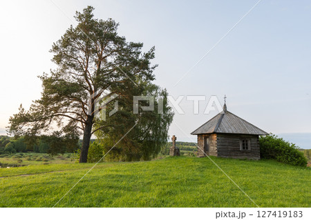 A picturesque ancient wooden chapel surrounded by lush greenery 127419183