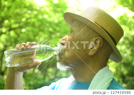 渓流で水分補給をする老人 127419398