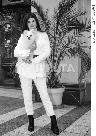 A girl holds a white fluffy dog ​​in her arms 127419961