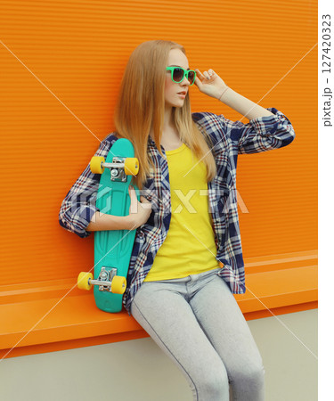 Stylish young woman with skateboard, modern teenage girl posing on city street 127420323