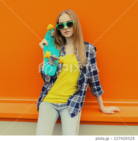 Stylish young woman with skateboard, modern teenage girl posing on city street 127420328