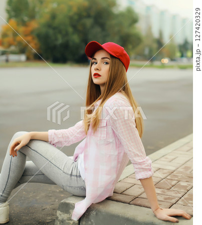 Stylish young woman sitting outdoors, modern teenage girl posing on city street 127420329