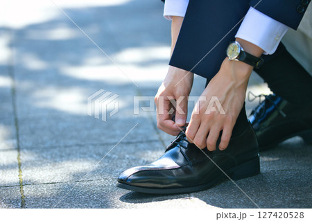 ビジネスシューズの靴紐を結ぶスーツの若い男性の足元 127420528