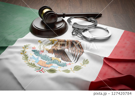Gavel and Handcuffs Resting on a Tattered and Dirty Mexican Flag. 127420784