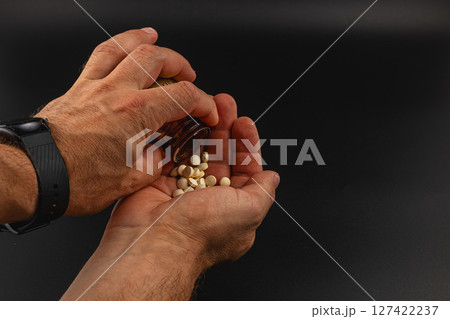 Hands pouring pills from a bottle into an open palm 127422237