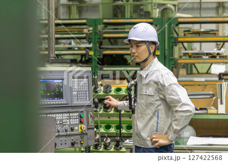 工場の操作盤で機械を操作する作業員 工場の操作盤で機械を操作する作業員 127422568