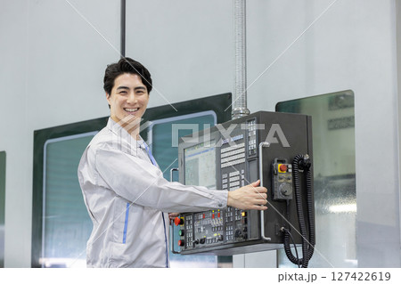 工場の操作盤の前で働く男性作業員 127422619