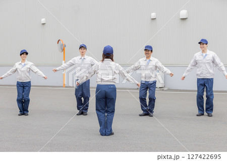 工場の前で体操する作業員グループ 127422695
