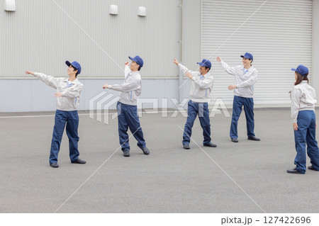 工場の前で体操する作業員グループ 127422696