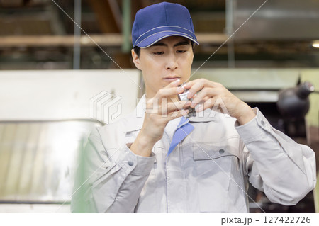 工場で旋盤加工品・フライス加工品を確認する男性作業員 工場で旋盤加工品・フライス加工品を確認する男性作業員 127422726