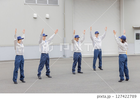 工場の前で体操する作業員グループ 127422789