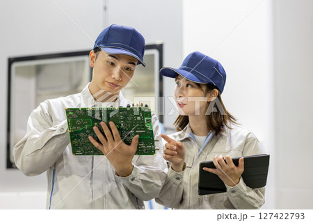 工場でタブレットを使って製品を検査する男女作業員 127422793