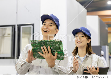 工場でタブレットを使って製品を検査する男女作業員 127422794