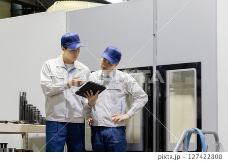 タブレットPCを持って機械を点検する作業員グループ 127422808