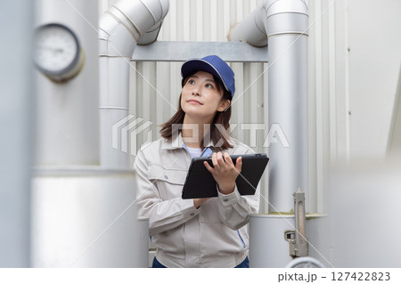 屋外機械を点検する女性作業員 127422823
