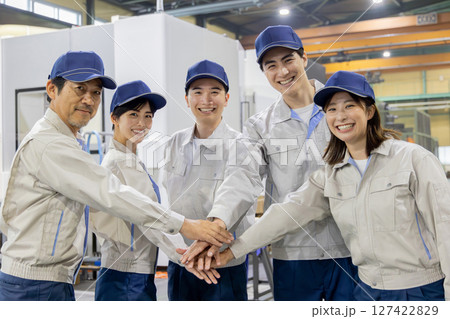 工場の中で円陣を組む作業員グループ 127422829