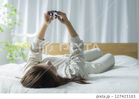 ベッドでスマホを見る女性 127423183