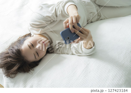 ベッドでスマホを見る女性 ベッドでスマホを見る女性 127423184