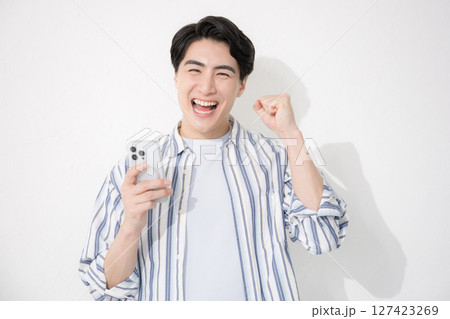 シャツを着た男性　カメラ目線スマホでガッツポーズとやる気 127423269