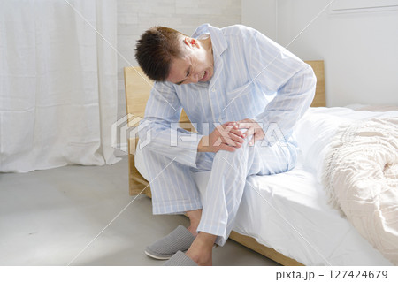 膝が痛いパジャマを着た中年の男性 膝が痛いパジャマを着た中年の男性 127424679