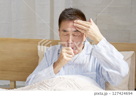 咳をするパジャマを着た中年の男性 127424694