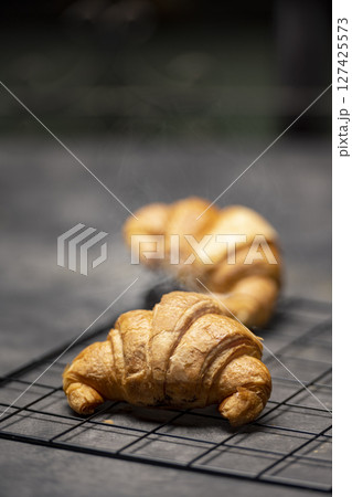 Croissants on a cooling tray with a black background Croissants on a cooling tray with a black background 127425573