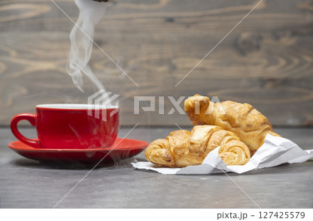 Croissants and cup of coffee on the table with wooden background Croissants and cup of coffee on the table with wooden background 127425579