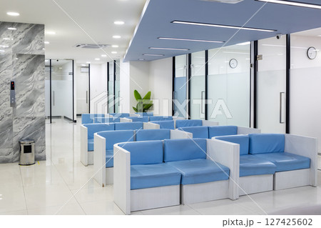 Row of comfortable couches in waiting room for patients with doctor appointments in a modern healthcare clinic or hospital 127425602