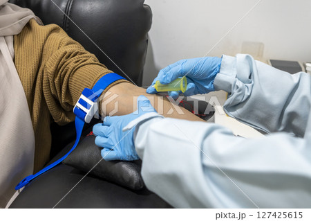 Closeup view of doctor hand in blue gloves taking a blood sample from a patient in the hospital. Healthcare and medical concept 127425615