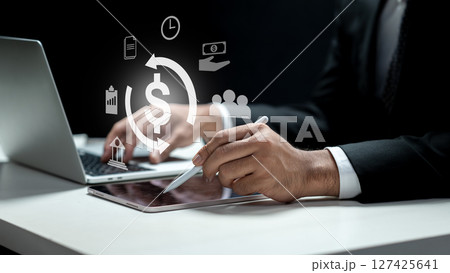 Businessman using a laptop while showing a currency icon on the tablet screen. Technology innovation on a virtual screen. Concept of payroll Businessman using a laptop while showing a currency icon on the tablet screen. Technology innovation on a virtual screen. Concept of payroll 127425641