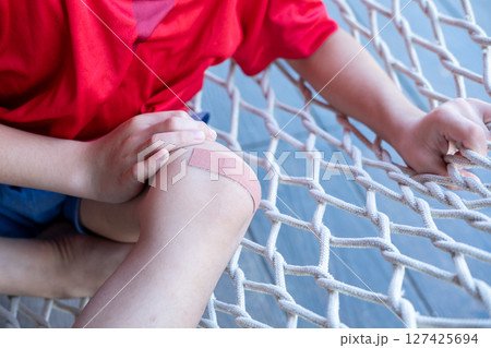 Asian boy sitting on a net with wound dressing plaster. Asian boy sitting on a net with wound dressing plaster. 127425694