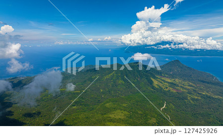 Top view of mountain with lush green forest in Camiguin Island. Blue sky and clouds. Philippines. Top view of mountain with lush green forest in Camiguin Island. Blue sky and clouds. Philippines. 127425926