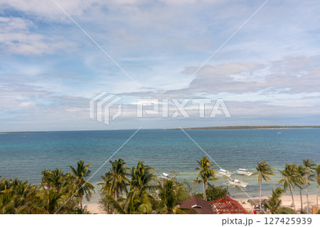 Beach view from above, palm trees and ocean waves crashing on white sands. Baigad Lagoon Beach. Bantayan Island, Cebu, Philippines. 127425939