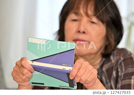 預金通帳 貯金通帳の残高を確認するシニア 預金通帳 貯金通帳の残高を確認するシニア 127427035