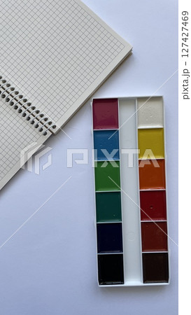 Top View of Watercolor Paint Set and Spiral Notebook on White Background. Back to School Creative Concept. Stationery for Drawing and Education. 127427469