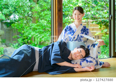 縁側で膝枕を楽しむ男女が浴衣姿で笑顔を見せる夏の和やかな日常シーン 縁側で膝枕を楽しむ男女が浴衣姿で笑顔を見せる夏の和やかな日常シーン 127427880