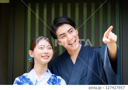 浴衣姿の男女が並んで立ち男性が指差しながら女性と楽しそうに話す夏の旅先でのひとコマ 浴衣姿の男女が並んで立ち男性が指差しながら女性と楽しそうに話す夏の旅先でのひとコマ 127427957