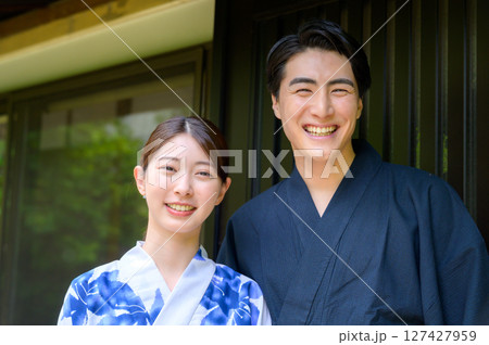 笑顔の男女が和風家屋の前で爽やかに並ぶ浴衣ポートレートで夏のひとときを表現するカット 127427959
