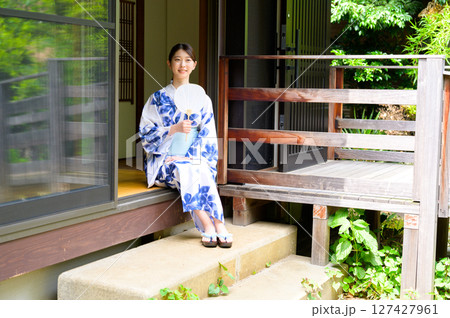 和風旅館の縁側に腰掛けた浴衣姿の女性がうちわを手に静かな時間を楽しむ夏の和のひととき 127427961