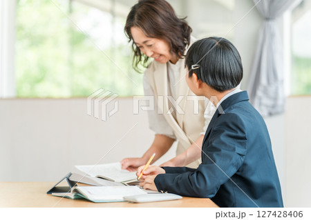 タブレットを使い勉強をする制服姿の小学生・中学生・高校生とママ・母親・教師・先生・講師 127428406