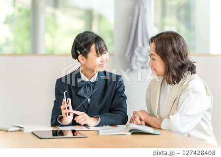 勉強をする制服姿の小学生・中学生・高校生とママ・母親・教師・先生・講師 127428408