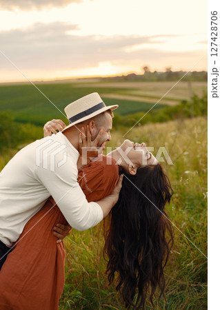 Couple in a field. Woman in a brown dress. Sunset background. 127428706