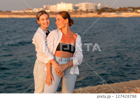 Women Beach Sunset Vacation: Two women laughing by the sea at sunset during a summer vacation. 127428798