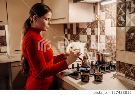 Woman Kitchen Coffee Preparation: Evening domestic scene showing woman making coffee in her kitchen. 127428816