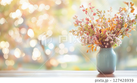 Elegant autumn floral arrangement in warm, muted tones against a bokeh background of golden light. 127428939